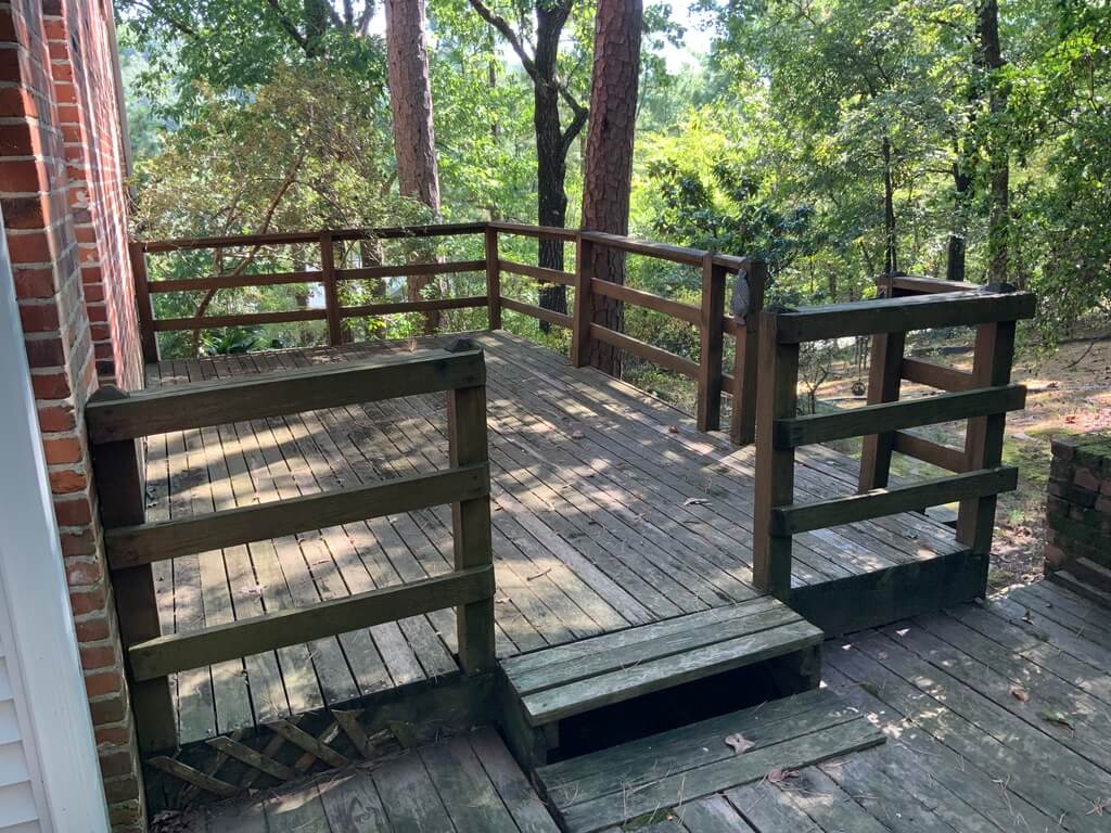 Old rotten deck on side of red brick home